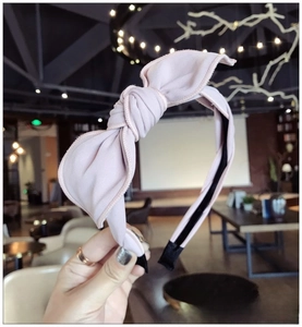 Detail of light pink fabric bow headband showing textured knot and black anti-slip tip