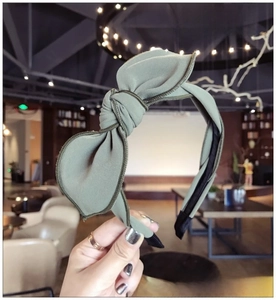 Detail of olive green fabric headband featuring a textured bow and non-slip inner lining