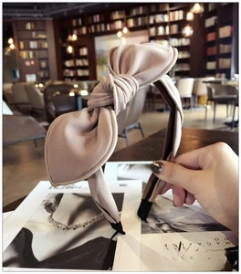 Detail of beige fabric headband with bunny ear bow shown in a cozy cafe setting