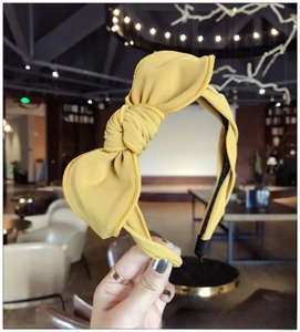 Detail of yellow fabric headband featuring a rabbit ear bow and textured twill material