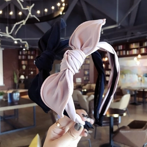 Minimalist fabric bow headbands in black and pink colors held against a cafe background