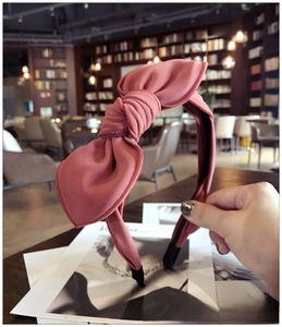 Detail of salmon pink fabric headband with a large bow against a cozy interior backdrop