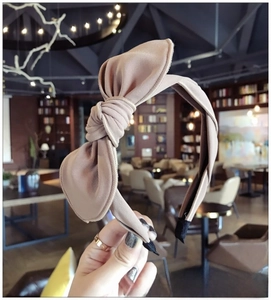 Detailed close-up of a milk tea brown fabric headband with a large knotted bow design