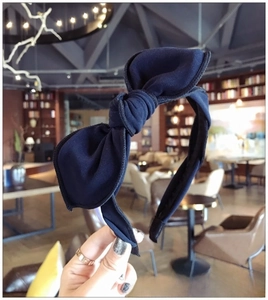Detail of navy blue knitted fabric headband featuring an oversized bow knot design