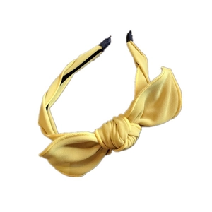 Minimalist yellow fabric headband with large rabbit ear bow design on white backdrop