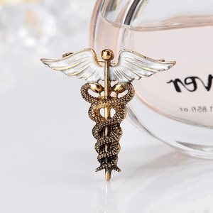Caduceus brooch in bronze alloy with white enamel wings and detailed snake scales texture