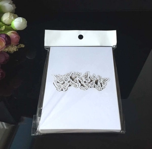 Close-up of laser-cut white butterfly place cards for weddings on a dark reflective surface