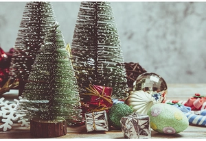 Close-up of sisal Christmas trees with snow tips, mini gift boxes and festive ornaments