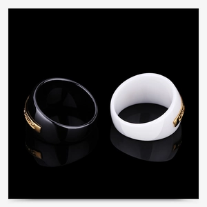Macro detail of black and white ceramic rings with gold crystal inlay and mirror reflection