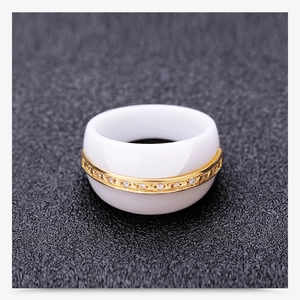 Macro shot of white ceramic ring with gold center band and inlaid white diamonds