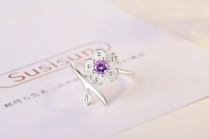 Detailed close-up of a silver cherry blossom ring featuring a purple zircon stone center