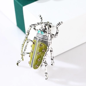 Detail of vintage enamel beetle brooch with green rhinestones next to a white gift box