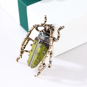 Detailed macro view of vintage gold enamel beetle brooch resting on a white gift box