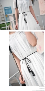 Detail of a thin black braided tassel waist rope on a white pleated summer dress