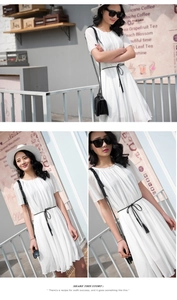 Detail view of a white chiffon dress featuring a thin black waist chain with elegant tassels