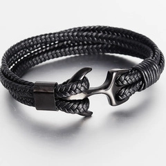 Detail shot of black braided leather bracelet featuring a dark metal anchor clasp