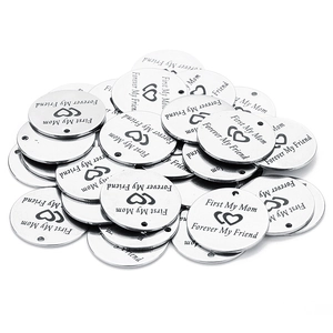 Macro shot of silver stainless steel round charms with heart and friendship engraving
