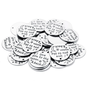 Macro shot of silver stainless steel round charms with I love you to the moon & back engraving