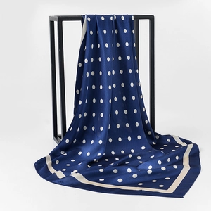 Detailed view of dark blue silk-like square scarf with white polka dots and cream borders
