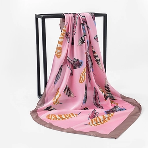 Detailed view of pink floral silk scarf featuring colorful feather patterns and smooth texture