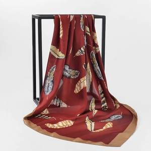 Detailed close-up of wine red silk scarf with feather print draped over a black frame