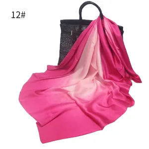 Detail of silk-like gradient scarf in rose pink and light pink draped over a handbag