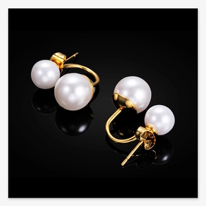Macro detail of 10mm double pearl stud earrings with elegant gold finish on black base
