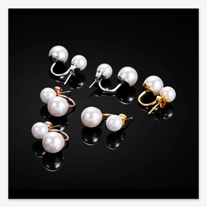 Detail of double pearl stud earrings in gold, silver, and rose gold on black background