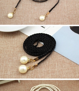 Detail of woven black dress belt featuring elegant pearl charms and gold accents