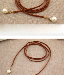 Close-up of brown braided faux leather belt with large pearl pendants and rhinestones