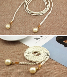 Detail of woven rope belt with large faux pearls and gold hardware on linen background