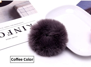 Plush faux rabbit fur scrunchie in coffee gray displayed with a fashion magazine