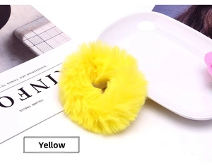 Macro shot of bright yellow faux fur scrunchie with fluffy texture on a styled background