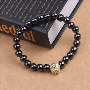 Gros plan d'un bracelet en perles noires avec tête de lion dorée sur un livre ancien