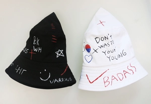 Detail of street-style bucket hat featuring graffiti heart patterns and urban text