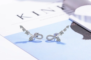 Close-up of S925 silver infinity arrow earrings with white zircon on a magazine