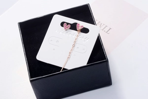 Detail view of pink heart earrings with long chain in a black luxury gift box