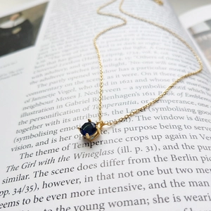 Detailed view of sapphire blue gemstone necklace with gold chain on open book pages