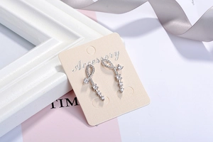 Detailed view of silver zircon tassel earrings featuring an infinity symbol on card