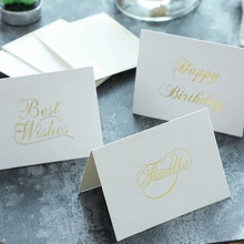 Close-up of white paper greeting cards with gold foil lettering for DIY scrapbooking