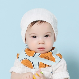 Détail d'un bonnet en maille côtelée blanche et d'un bavoir bandana pour bébé