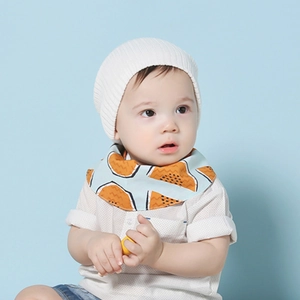 Détail d'un bavoir bleu à motifs et bonnet en maille blanche sur un bébé mannequin