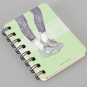 Detail of green A7 spiral notebook featuring cartoon illustration and Today is the Day text