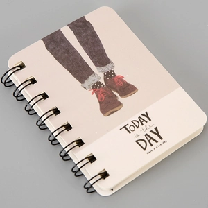 Close-up of A7 spiral notebook with cartoon legs illustration and motivational text