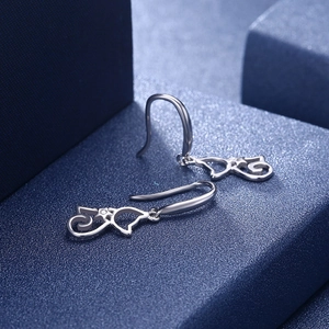 Macro shot of silver hollow-out cat earrings with sparkling zircon on a blue display