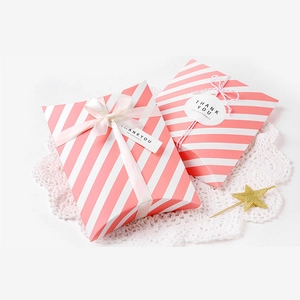 Pink striped pillow gift boxes with ribbons and thank you tags on white lace decor