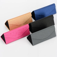Detail view of foldable triangular glasses cases in five assorted fabric texture colors