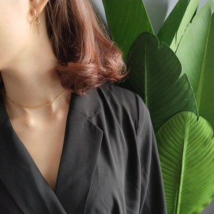 Detail of 925 sterling silver gold chain necklace and key earrings on model in black suit
