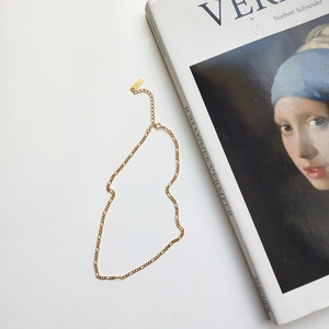 Detail of a gold Figaro chain necklace with lobster clasp and adjustable extension link
