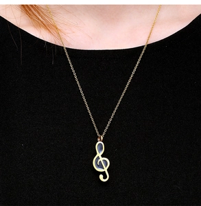 Detailed view of a gold musical note pendant urn necklace worn by a fashion model